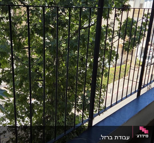 מעקה סורגים ישרים ממתכת שחורה המותקן במרפסת
